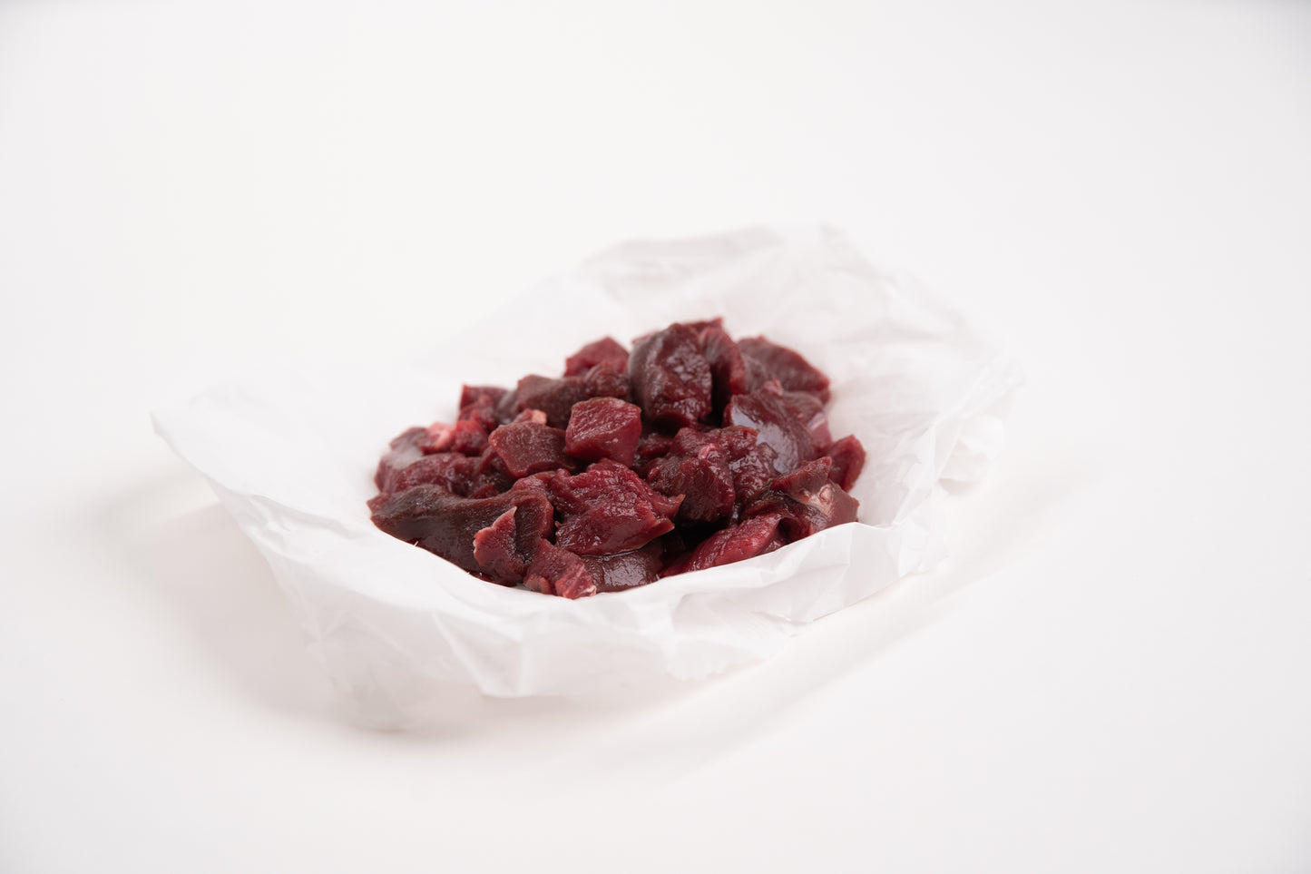 Diced raw elk meat on a white background