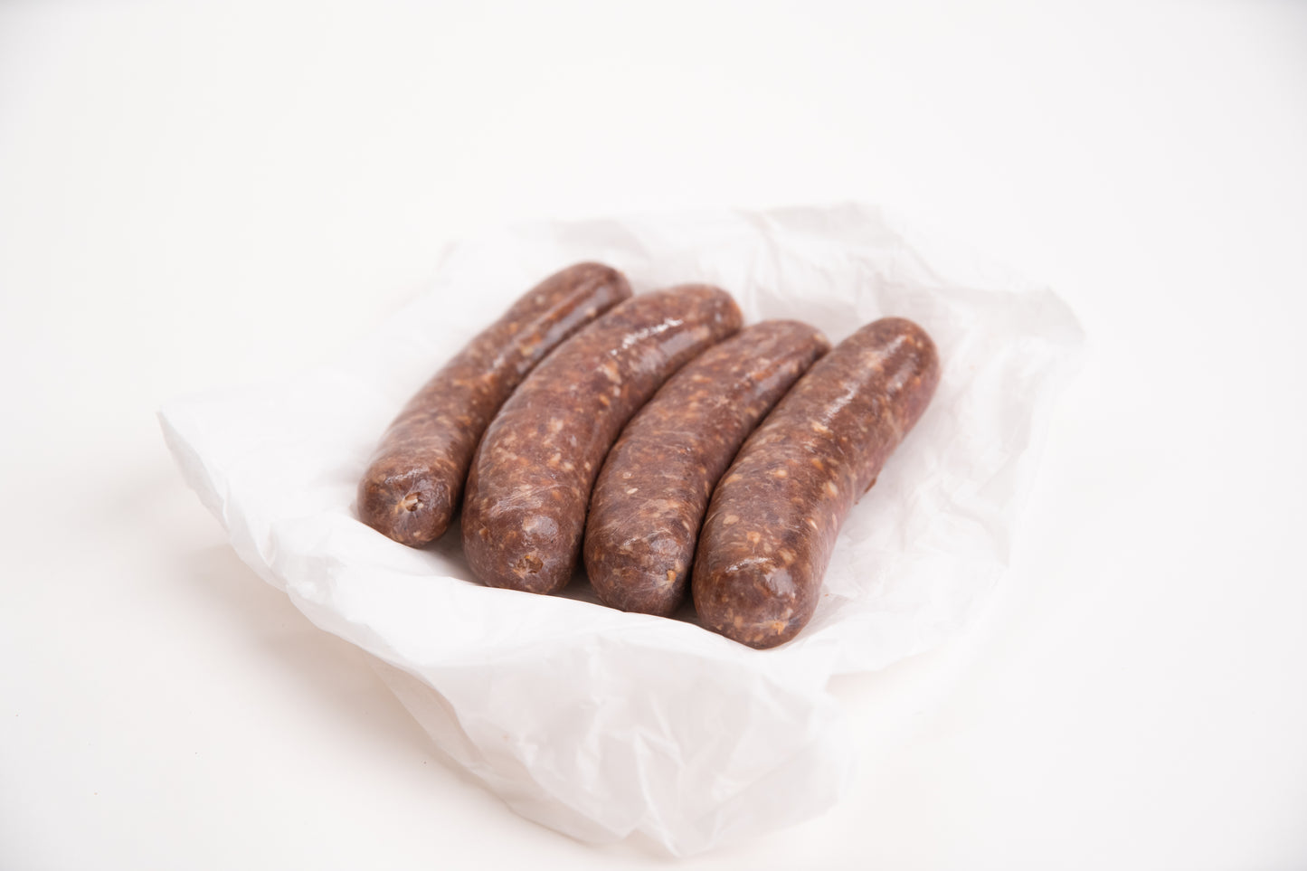 Four raw elk meat sausages on a white background