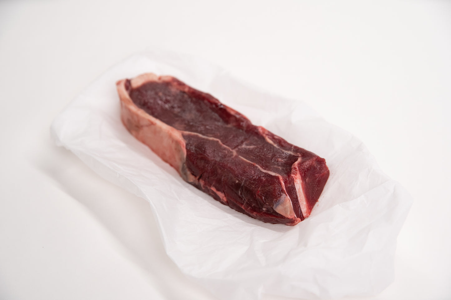 Raw elk steak on a white background