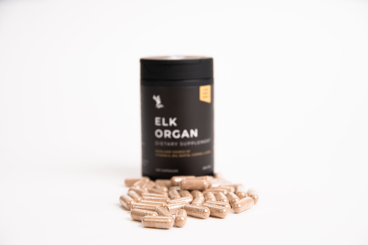 Elk Organ Dietary Supplement with capsules sitting in front of black bottle