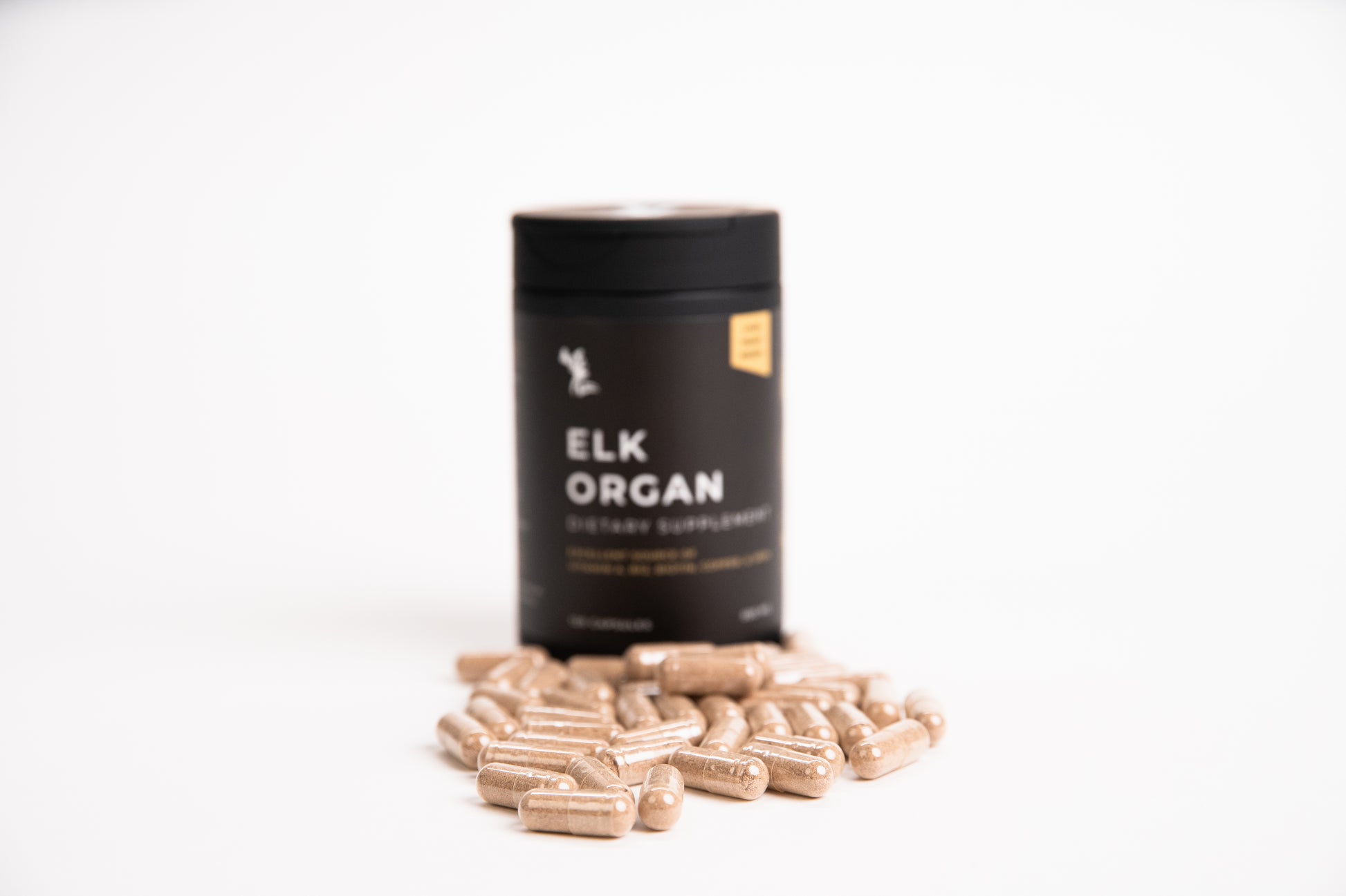 Elk Organ Dietary Supplement with capsules sitting in front of black bottle