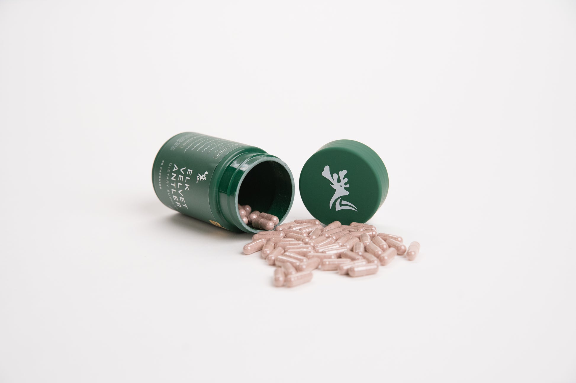Elk Velvet Antler Dietary Supplement with capsules pouring out of green bottle