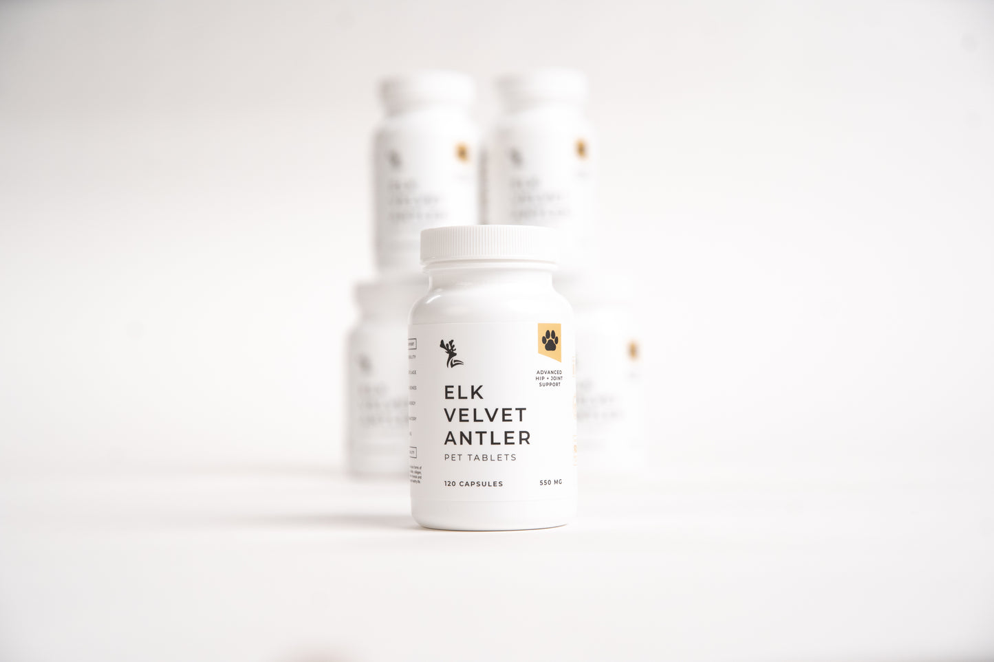 Stacked white bottles of Elk Velvet Antler Pet Tablets on a white background