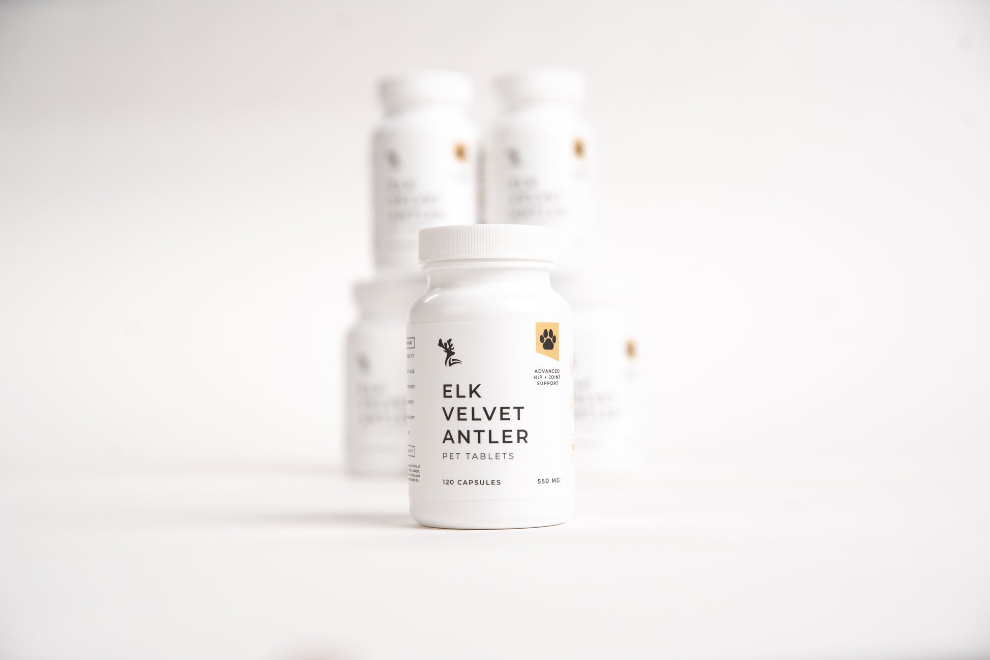 Stacked white bottles of Elk Velvet Antler Pet Tablets on a white background