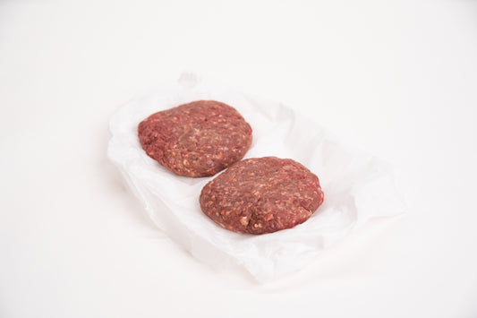 Two raw elk burger patties on a white background